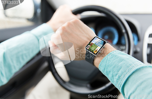 Image of close up of male hands with smartwatch driving car