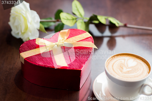 Image of close up of gift box and coffee cup on table