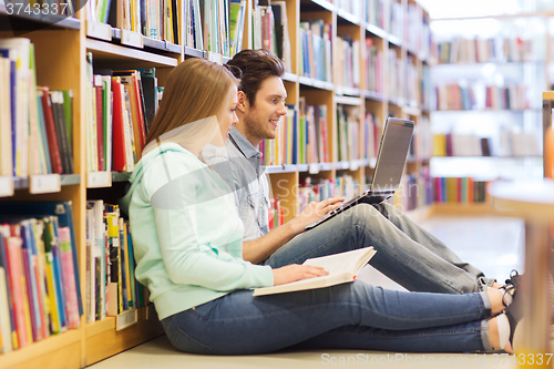 Image of happy students with laptop in library