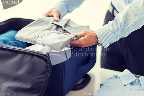 Image of businessman packing clothes into travel bag