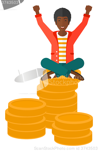Image of  Happy businessman sitting on coins.