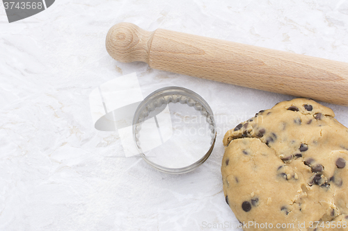 Image of Chocolate chip cookie dough with rolling pin and cookie cutter 
