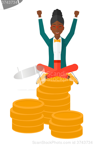 Image of Happy business woman sitting on coins.