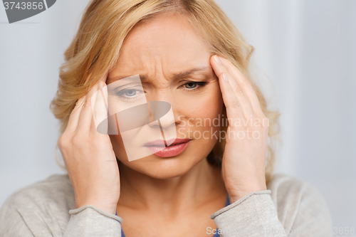 Image of unhappy woman suffering from headache at home