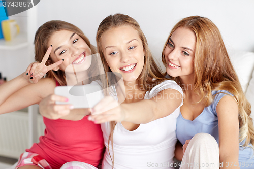 Image of teen girls with smartphone taking selfie at home