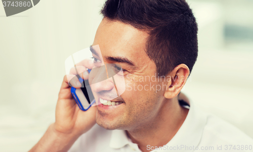 Image of happy man calling on smartphone at home