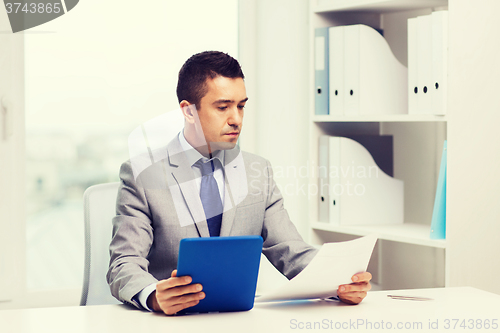 Image of businessman with tablet pc and papers in office