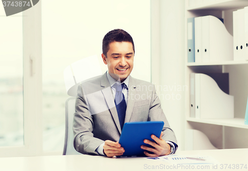 Image of smiling businessman with tablet pc in office