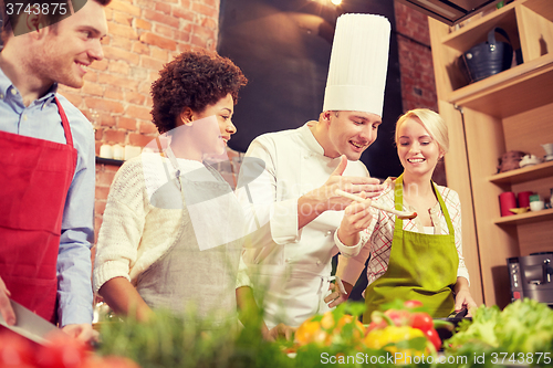 Image of happy friends and chef cook cooking in kitchen