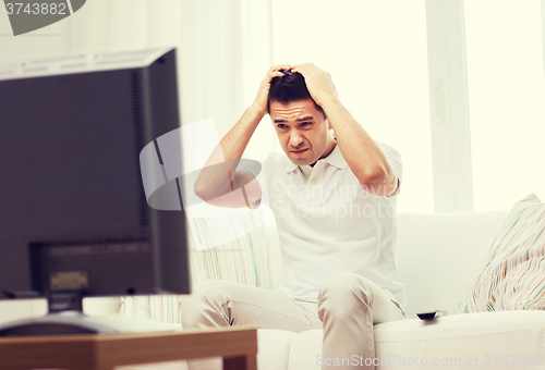 Image of disappointed man watching tv at home