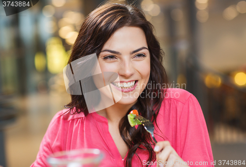 Image of happy young woman having dinner at restaurant