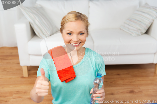 Image of happy woman drinking water and exercising at home