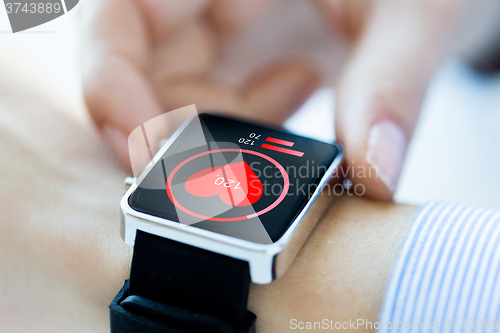 Image of close up of hands with heart icon on smartwatch