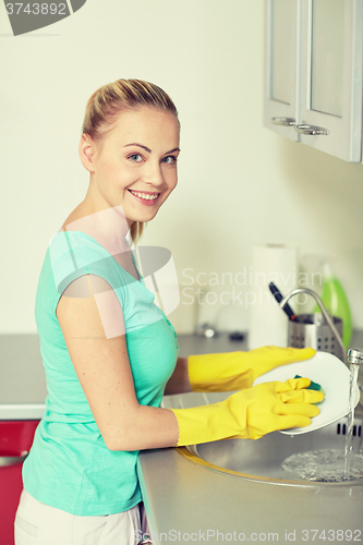 Image of happy woman washing dishes at home kitchen