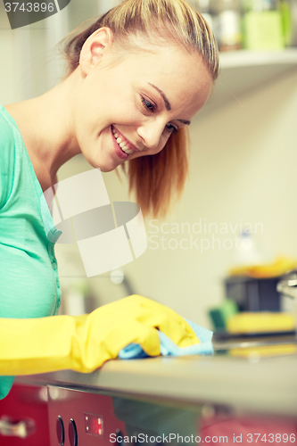 Image of happy woman cleaning cooker at home kitchen