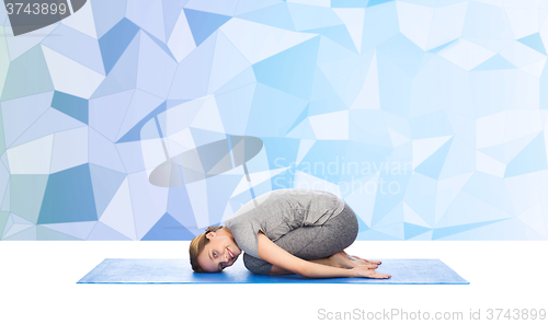 Image of happy woman making yoga in child pose on mat