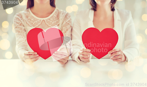 Image of close up of happy lesbian couple with red hearts