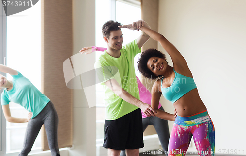 Image of group of smiling people stretching in gym