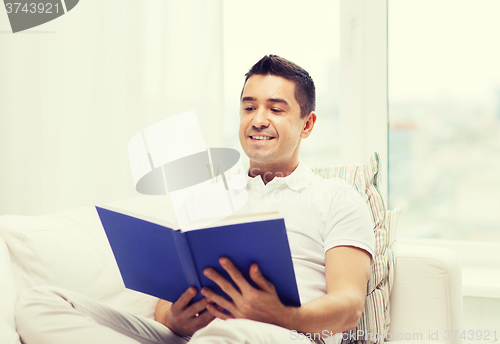 Image of happy man reading book at home