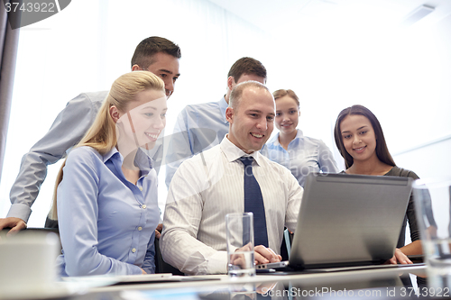 Image of smiling business people with laptop in office