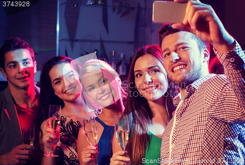 Image of friends with glasses and smartphone in club