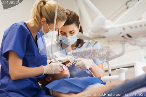 Image of female dentists treating patient girl teeth