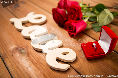 Image of close up of diamond ring, red roses and word love