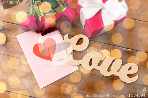 Image of close up of gift box, red roses and greeting card