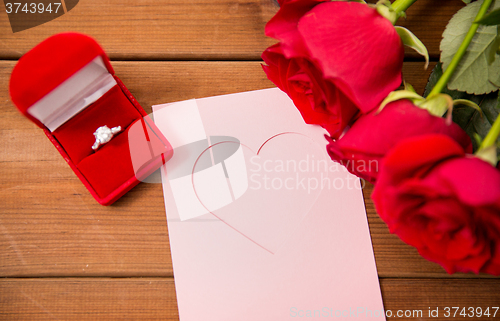 Image of close up of diamond ring, roses and greeting card