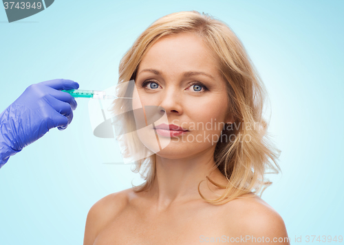 Image of woman face and beautician hand with syringe