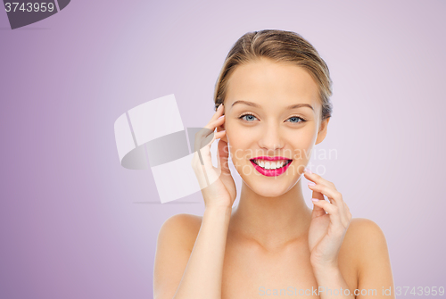 Image of smiling young woman with pink lipstick on lips