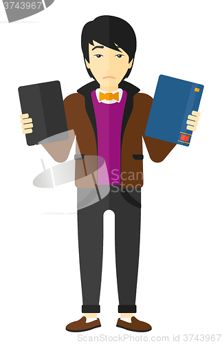 Image of Man choosing between book and tablet computer.