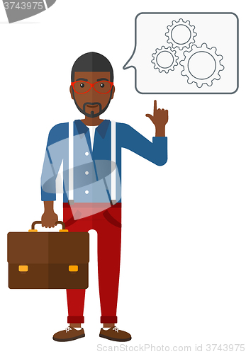 Image of Businessman pointing at cogwheels.