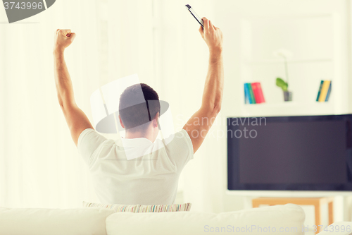 Image of man watching tv and supporting team at home