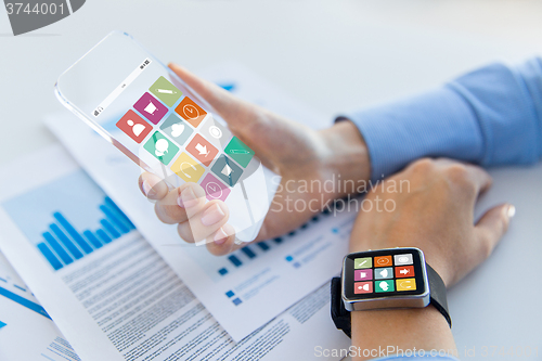 Image of close up of hands with smart phone and watch icons