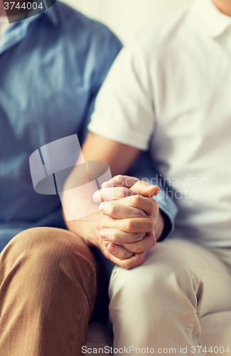 Image of close up of happy male gay couple holding hands