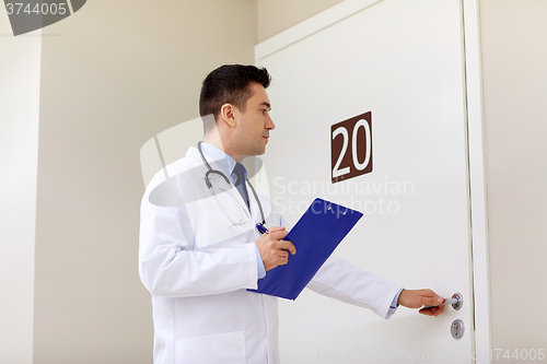 Image of doctor with clipboard opening hospital ward door