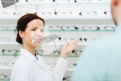 Image of optician showing glasses to man at optics store