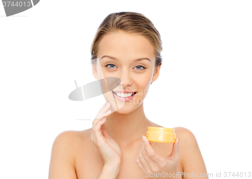 Image of happy young woman applying cream to her face