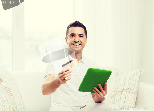 Image of smiling man working with tablet pc at home