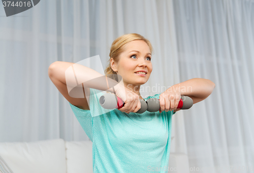 Image of woman exercising with dumbbells on mat at home