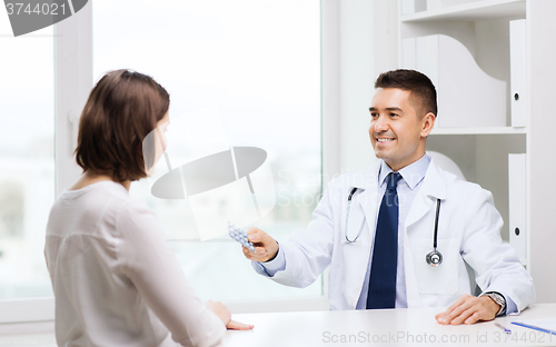 Image of smiling doctor giving pills to woman at hospital