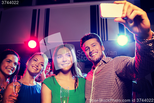 Image of friends with glasses and smartphone in club