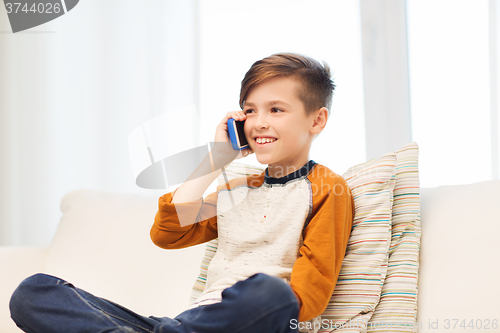 Image of happy boy calling on smartphone at home