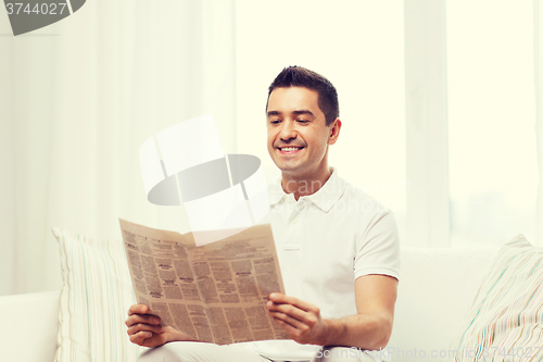 Image of happy man reading newspaper at home