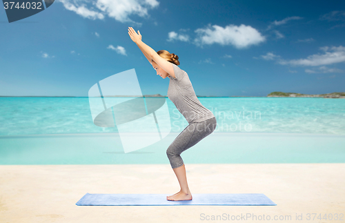 Image of woman making yoga in chair pose on mat