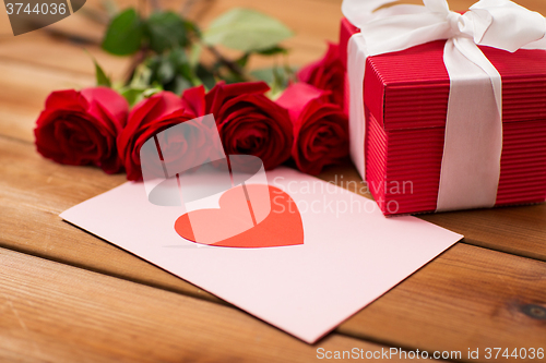 Image of close up of gift box, red roses and greeting card