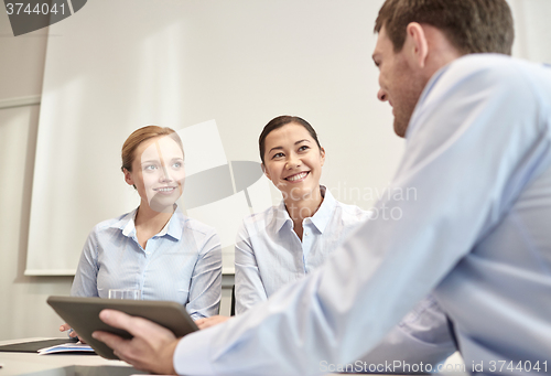 Image of smiling businesspeople with tablet pc in office