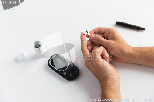 Image of close up of man checking blood sugar by glucometer