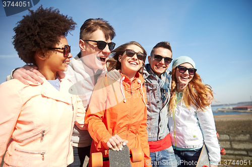 Image of happy teenage friends with longboards on street